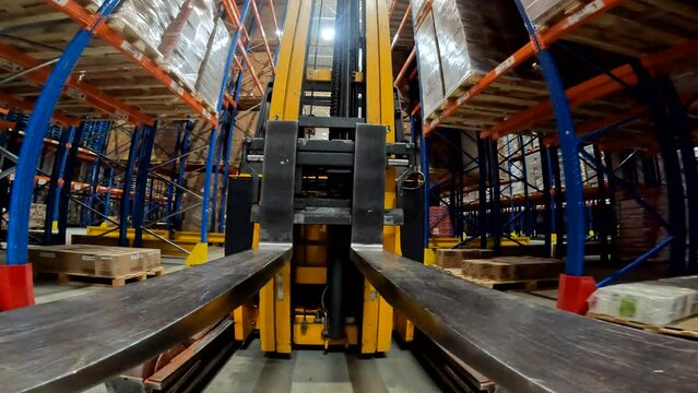Forklift fork close-up. The load lifter rides on the warehouse pov. Modern forklift in a large warehouse
