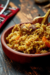 Classic pilaf with beef, garlic and carrots in a clay plate on a wooden background. Rustic