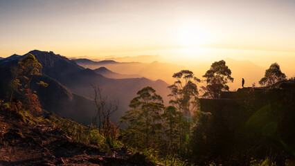 Silhouette of a woman watching the sunrise at Dolphin's nose in Kodaikanal, India