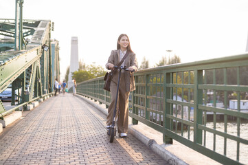 Portrait of young business woman with an electric scooter to work over bridge in modern city  background
