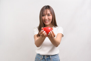 Portrait of young asian woman holding holding red heart shape over white background studio