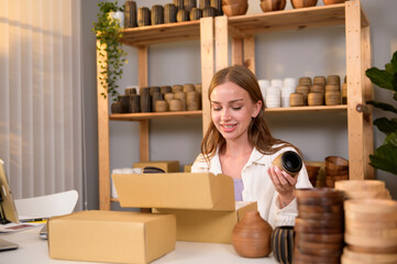 A young pretty woman entrepreneur checking and packaging craft products selling to customers in her shop