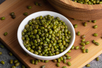Dry green beans on wooden bowl and spoon. Organic raw green mung beans. Vigna radiata.