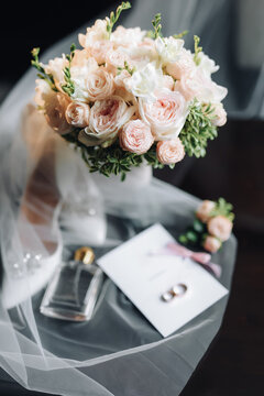 The wedding invitation contains two gold wedding rings of the bride and groom in yellow gold. Nearby lies a bridal bouquet, perfume, shoes. High quality photo