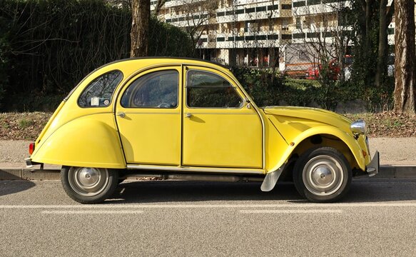 Udine, Italy. March 13, 2023. Vintage yellow Citroen 2Cv 6 at the roadside. Side view.