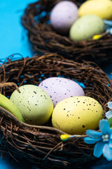 Easter eggs in wicker nest baskets on a blue background.