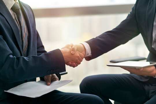 close-up shot of two asian business people shaking hands in office