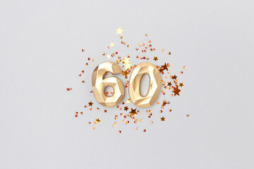 Gold colored number 60 and stars confetti on a blue background. Festive creative concept.