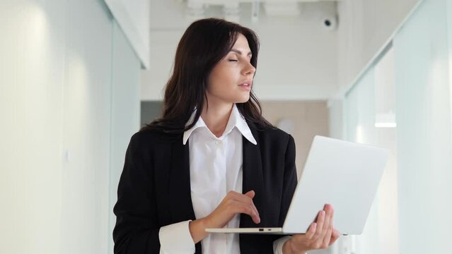 Professional female journalist is typing out a news report on her laptop in the office lobby. Focused determined to produce a high quality piece of work, convey important information to her audience.