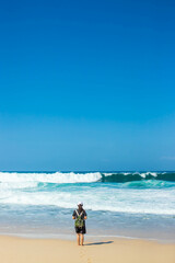 Photo of a woman standing alone at Beach during the day. Girl standing at sandy beach while sunny day.