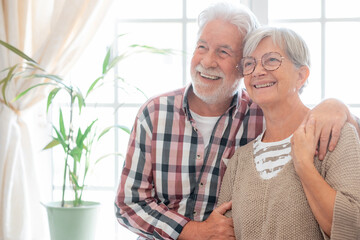 Happy senior couple embracing sitting at home. Modern retirees smiling, expressing happiness and carefree