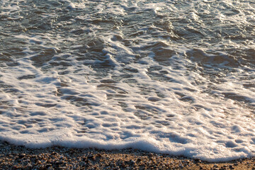 Small waves with foam on a pebble beach, Alanya