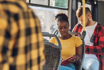 African american woman riding in a bus and reading a book