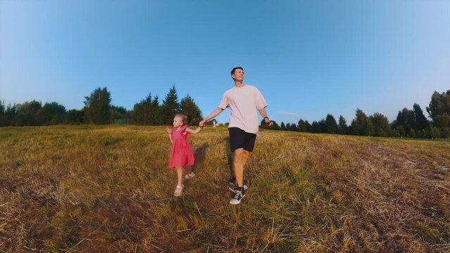 Dad and daughter are walking in the field, father and daughter are having fun in nature, daughter and father are walking in nature, shooting on a 360 camera