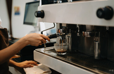 Cup and professional espresso machine pouring fresh coffee into a glass cup at cafe