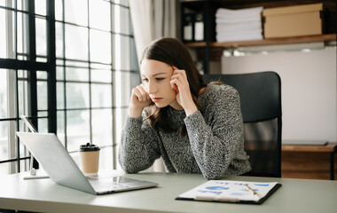  woman feeling migraine head strain.Overworked businesswoman financier while working on laptop and tablet at office.