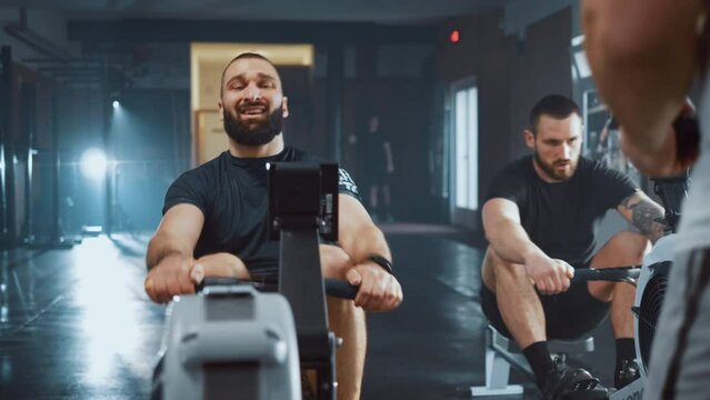 Young athletic men doing rowing machines workout at the gym
