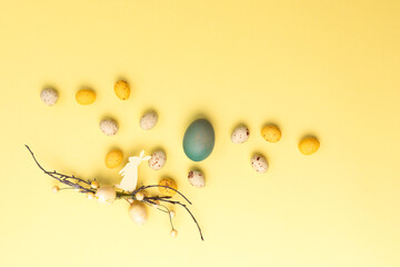 Obraz premium Colored eggs of different sizes on a yellow background. Symbol of the Easter holiday. Easter background. Flat lay