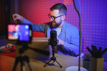 Joyful young man recording unboxing video in studio