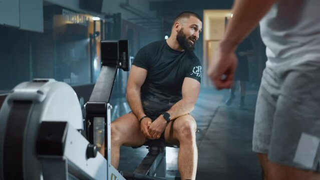 Male athlete adjusts a rowing machine in the gym