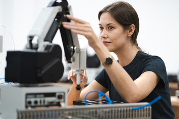 Computer science development engineer working on robotic arm connection at futuristic electronic technology center. Modern people training in industry 4.0 automated engineering. Empowerment woman.