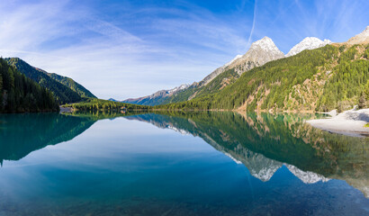 Morning light and still water with reflections at Lake Anterselva, also known as AntholzerSee or Lake Antholz, in South Tyrol, Italy.