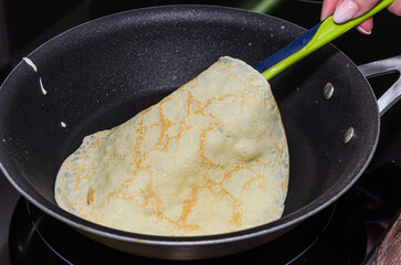 The cook is frying pancakes in a frying pan