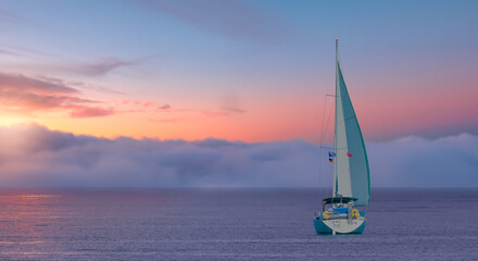 Obraz na płótnie Canvas Lonely yacht sailing in the Mediterranean sea at amazing sunset - Sailing luxury yacht with white sails in the Sea.