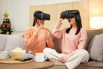 Young woman lesbian couple wearing sweater and VR goggles to pla - obrazy, fototapety, plakaty