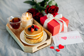 Holiday breakfast or brunch set served on gray bed with flowers, gift box and candle. Mother;s day,...