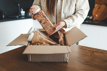 The girl holds a jar of granola in her hands, unpacking the goods