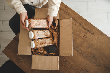 The girl holds a jar of granola in her hands, unpacking the goods