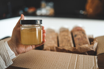 Fototapeta na wymiar Jar of honey in hand against the background of food delivery