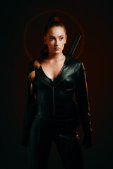 Fototapeta premium Woman, warrior and fashion outfit in studio for action, fight and safety from danger in a dark studio. Strong female model, assassin or killer in scifi leather cosplay costume with weapon for action