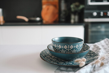 Set of stylish dishes with an ornament on the table against the backdrop of the kitchen