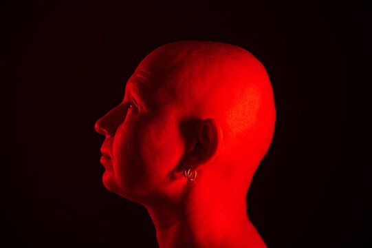 a man without hair on his head a creative portrait of a woman in red illumination