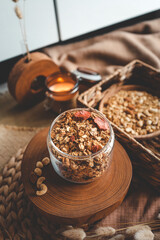 Homemade granola in a glass jar, against the background of milk, candle and decor, good morning concept