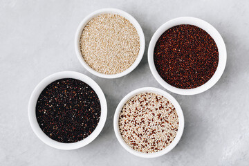 Quinoa mixed. Red black white quinoa seeds in bowls on gray stone background, top view.
