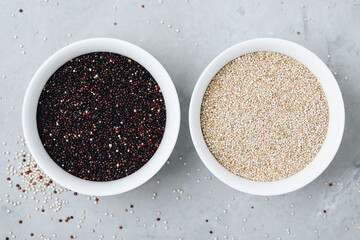 Quinoa mixed. Black white dried quinoa seeds in bowls on gray stone background, top view.