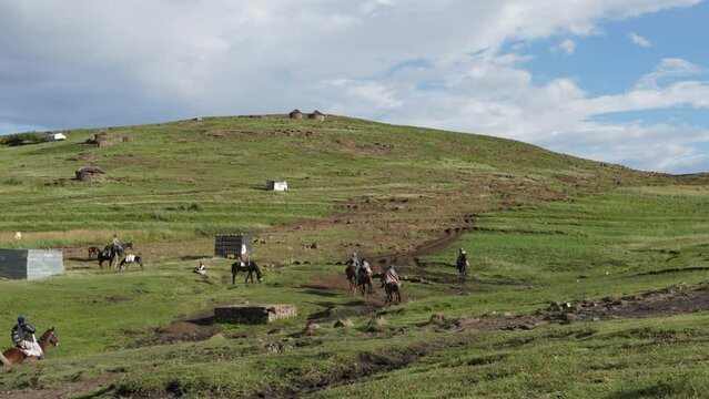 Lesotho farmers ride horses out of African village on their way home