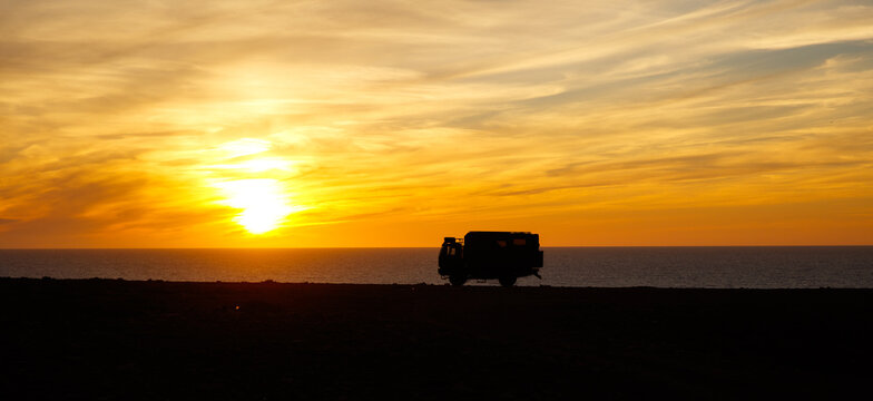 Adventurous road trip in motor home truck- sunset at the beach