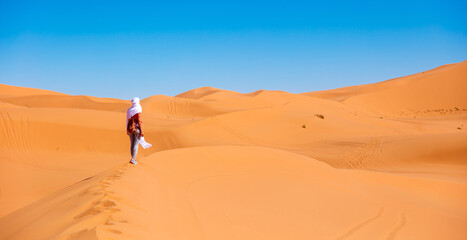 Young beautiful caucasian woman posing with white textile flying in the sahara desert in Morocco - obrazy, fototapety, plakaty