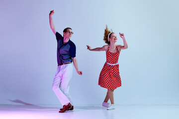 Young positive couple, man and woman in colorful costumes dancing retro style dances against...