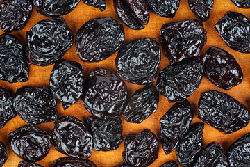 Dried plums on wooden background.