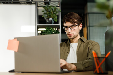 Modern Office Businessman Working on Computer. Portrait of Successful IT Software Engineer Working on a Laptop at his Desk. Diverse Workplace with Professionals. Front View Shot