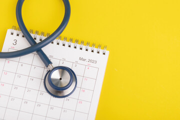 Health check up schedule concept, The idea of time for healthcare, Close up stethoscope and 2023 desk calendar on yellow. Yearly planning for health check up concept.