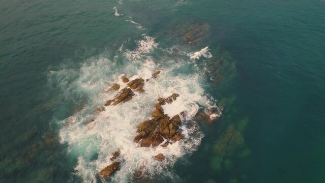 Aerial Circle Dolly Around Rocky Outcrop With Ocean Waves Breaking. Establishing Shot