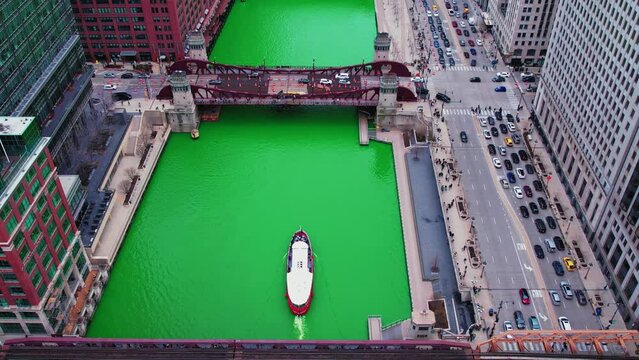 tilt up aerial above chicago river in downtown. During the St. Patrick's Day Parade cinematic 4k aerial reveal. Bascule bridge with chicago buildings in background Aerial 4k USA