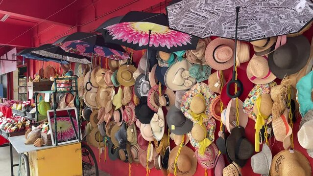 Pretty-looking hats' hanging on a bright red wall outside retail shops.