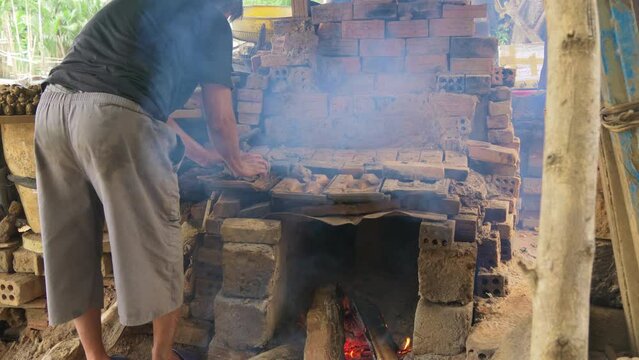 Potter arranges clay figurines ontop fire fed kiln in Than Ha village Vietnam Hoi An